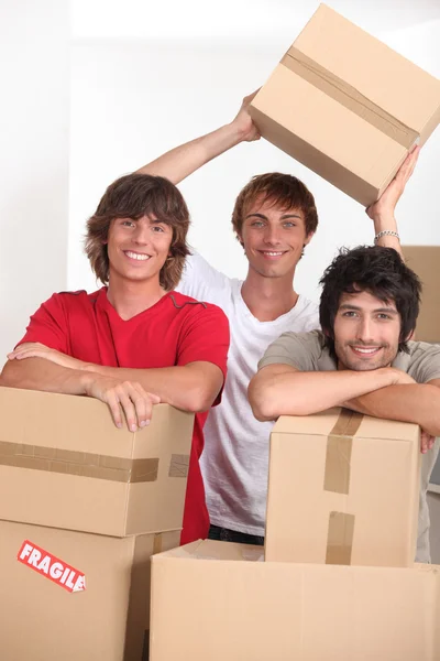 Tři mladé v místnosti plné kartony — Stock fotografie
