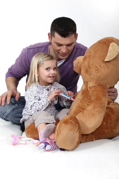 Une petite fille jouant au docteur avec son ours en peluche . — Photo