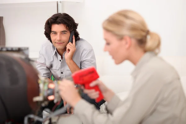 Женщина-техник работает, пока клиент разговаривает по телефону — стоковое фото