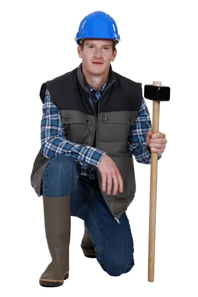 Workman crouching with hammer in hand — Stock Photo, Image