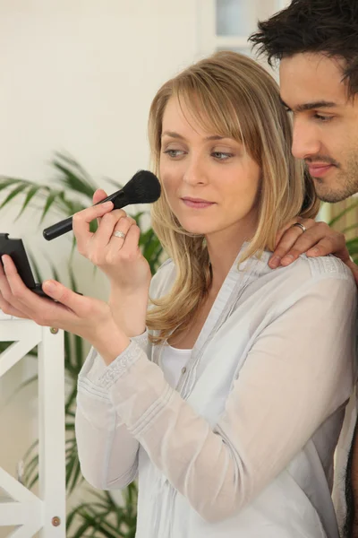 Woman applying blusher whilst boyfriend watches — Stock Photo, Image