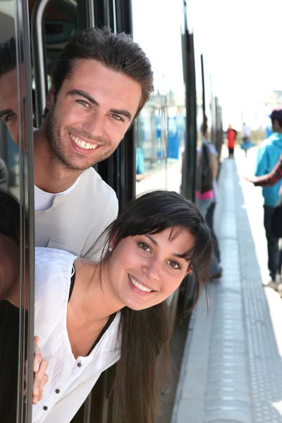 Couple leaning out of a tram door at a station — Stock Photo, Image