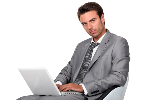 Бізнесмен сидів у кріслі, друкуючи на ноутбуці — стокове фото