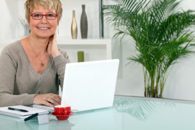 Woman working on her laptop at home clipart