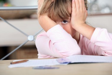 A little girl bored with her homework. clipart