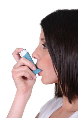 Woman using her inhaler clipart