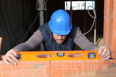 Man using spirit level to check wall clipart