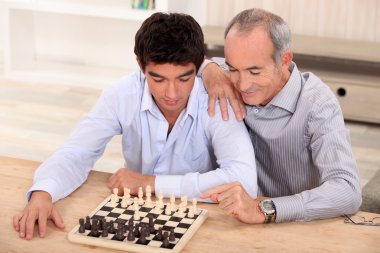 Father and son playing chess clipart