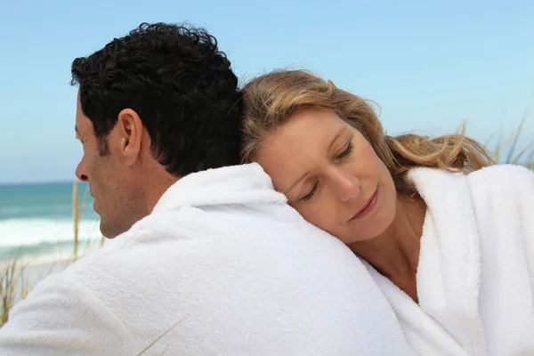 Couple by the sea in toweling robes — Stock Photo, Image
