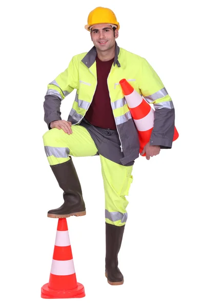 Trabalhador com pé em cima da sinalização cone — Fotografia de Stock