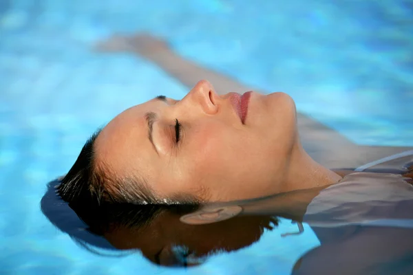 Brunette laying in pool — Stock Photo, Image