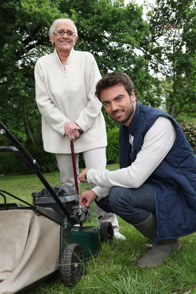 Sénior com jardineiro e cortador de grama — Fotografia de Stock