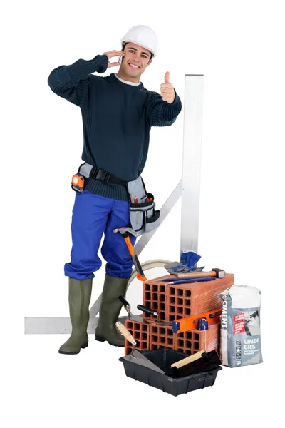 Um pedreiro posando com suas ferramentas e materiais de construção — Fotografia de Stock