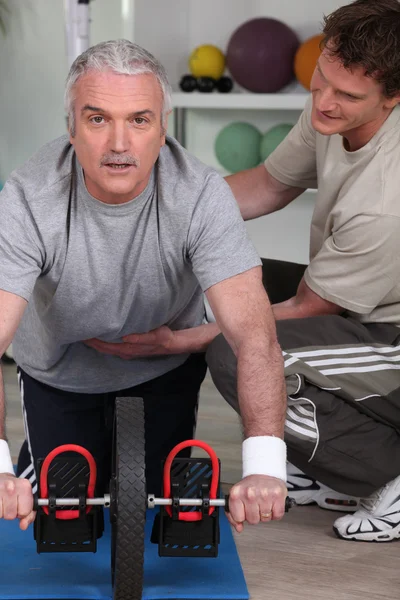 Middle-aged man with personal trainer — Stock Photo, Image