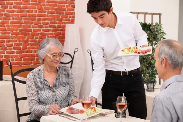 Senior koppel wordt geserveerd eten in een restaurant — Stockfoto