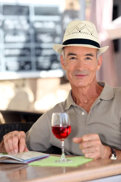 Anciano caballero turista bebiendo un vaso de rosa en un restaurante — Foto de Stock