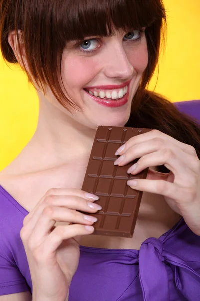 Gorgeous brunette crunching chocolate bar — Stock Photo, Image