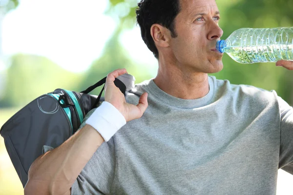 Athletic mature man drinking water from a bottle — Stock Photo, Image