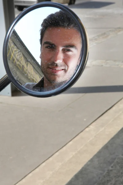 Человек, смотрящий в зеркало крыла скутера — стоковое фото