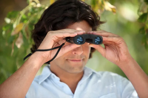 Man looking through a pair of binoculars — Stock Photo, Image