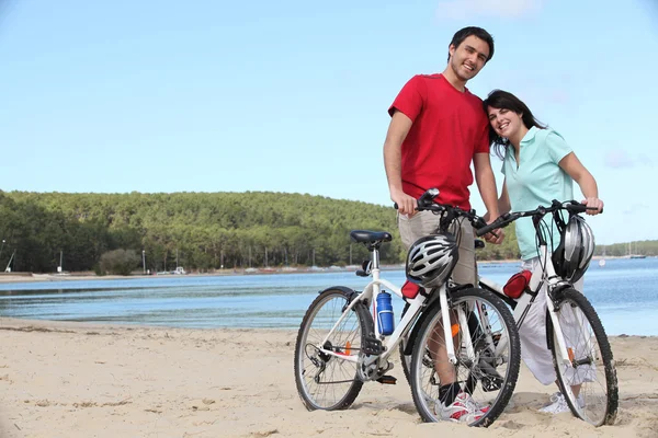 年轻夫妇与自行车的沙滩上 — 图库照片