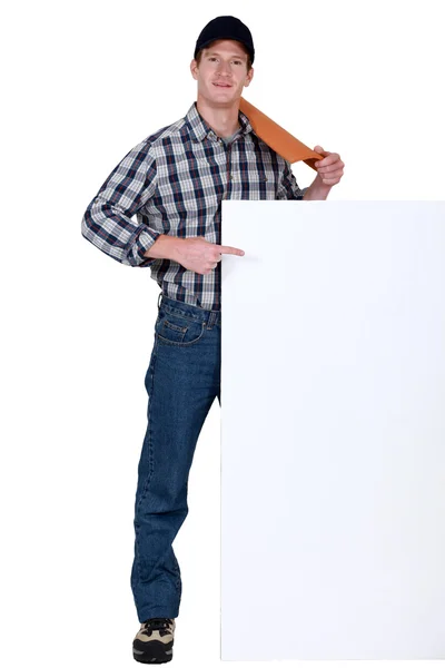 Roofer with tile pointing at blank poster — Stock Photo, Image