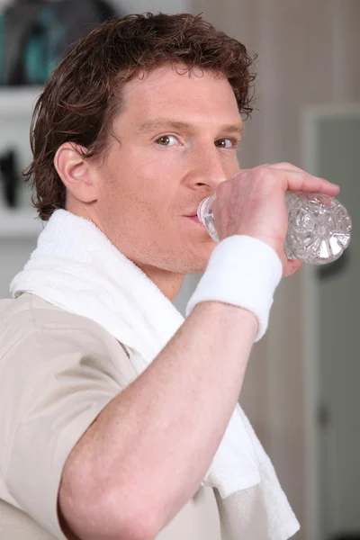 Man drinking from water bottle in gym — Stok fotoğraf