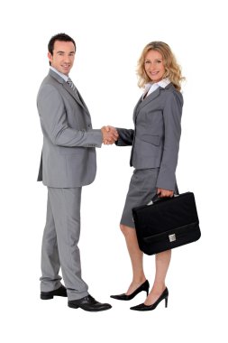 Smart suited man and woman shaking hands clipart