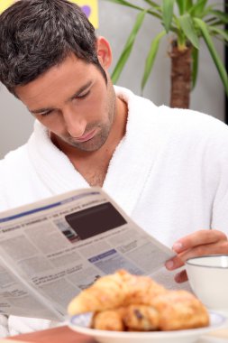 Man reading a journal over breakfast clipart