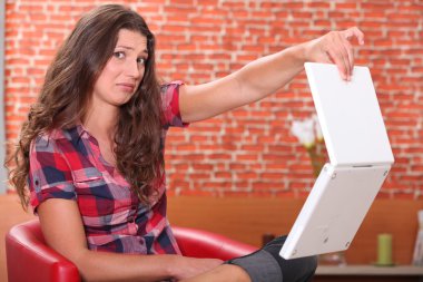 Woman holding her laptop disdainfully clipart