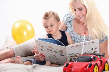 Woman reading a book to her son clipart