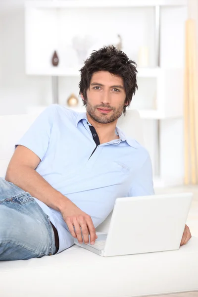 Mann liegt auf einem Bett und schaut auf seinen Laptop — Stockfoto