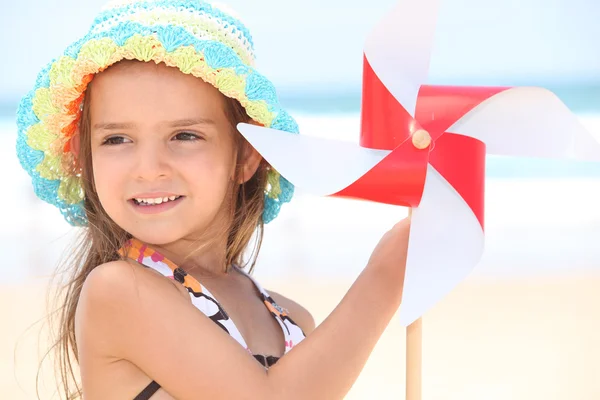 Liten flicka på stranden med leksak väderkvarn — Stockfoto