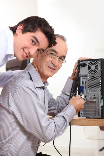 Grandson and grandfather connecting a computer — Stock Photo, Image
