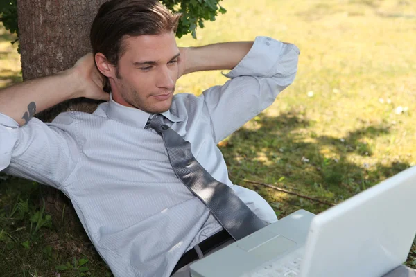 Hombre joven relajándose en la hierba con el ordenador portátil —  Fotos de Stock