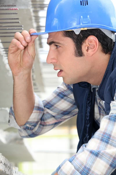 建設労働者の彼の帽子のつばに触れる — ストック写真