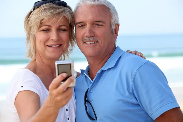 Ouder paar nemen een foto van zichzelf door de zee — Stockfoto