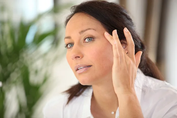 Mujer aplicando crema en su cara — Foto de Stock
