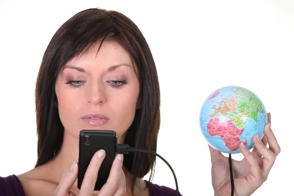 Woman charging battery of cell phone with globe — Stock Photo, Image