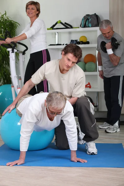 Older working out with a personal trainer in a gym — Stock Photo, Image