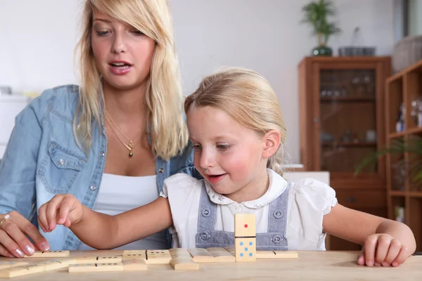 Young woman and her daughter playing dominoes Royalty Free Stock Images