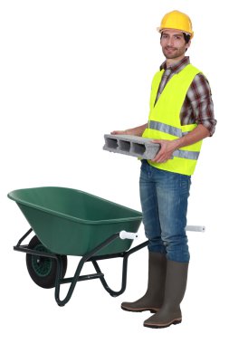 Man placing brick into wheelbarrow clipart