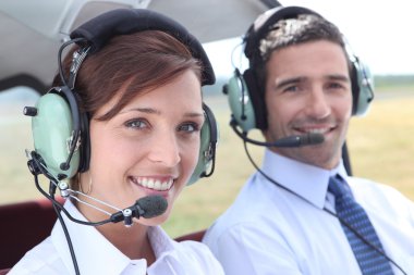 Man and woman wearing headsets in the open cockpit of a light aircraft clipart