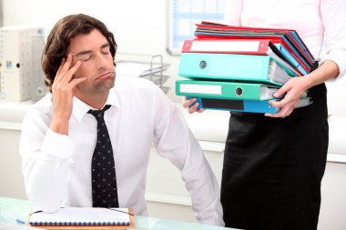Office worker overwhelmed by load of work clipart