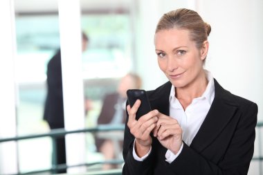 Blond business woman sending text message clipart