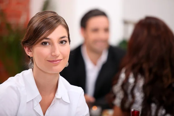 Concéntrate en una mujer sentada en un restaurante con otros comensales en el fondo — Foto de Stock