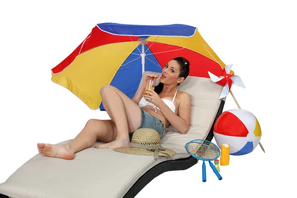 Brunette laying on lounger drinking cocktail — Stock Photo, Image
