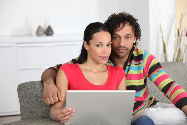 Gemischtes Paar zu Hause mit Laptop — Stockfoto