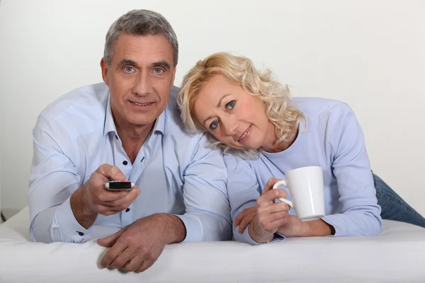 Casal de meia-idade assistindo televisão na cama — Fotografia de Stock