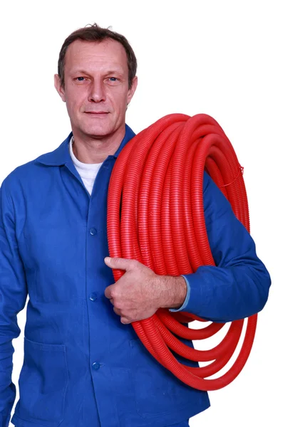 Fully-fledged plumber carrying red hose — Stock Photo, Image